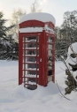 Old-style red telephone box under snow